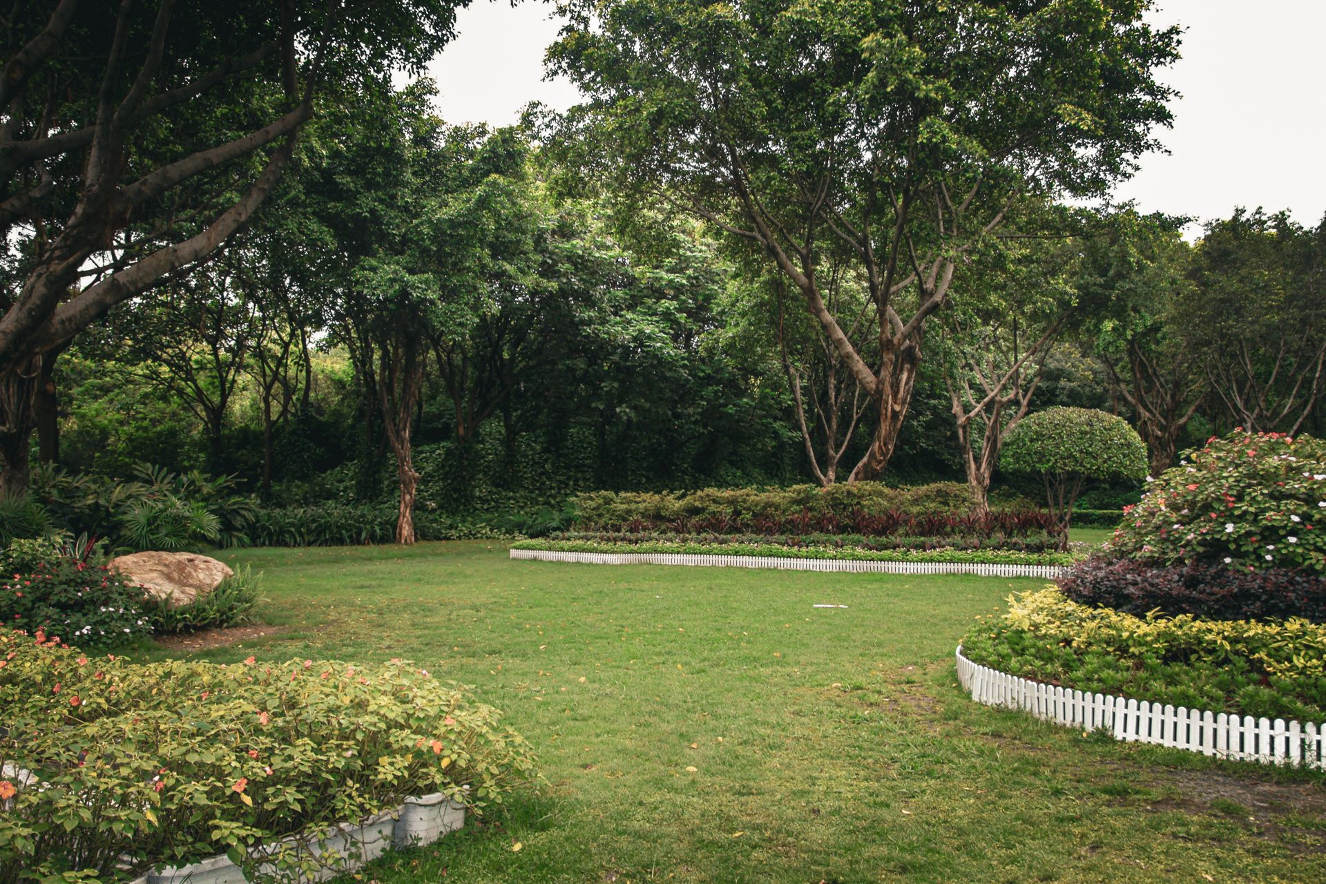 Garden with flower beds, manicured lawn and white border fencing